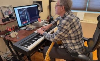 Ebben a képen John Beltzer, a Love Foundation Songs of Love Foundation egy elektronikus zongorabillentyűzeten található, és eltalálja a fenti számítógépes billentyűzetet. Egy számítógépes oktatóra néz, aki a zongora billentyűzet mögött található íróasztalon van. Egy gitár az ölében nyugszik.